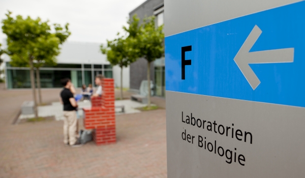 Bild Campus Rheinbach im Vordergrund Wegweiser mit Aufschrift "F - Laboratorien der Biologie"