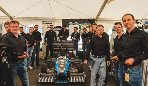 Motorsportteam mit Bolide in Zelt