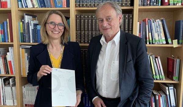 Professorin mit Urkunde neben Präsident