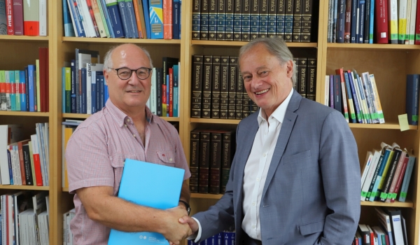 Professor neben Präsident vor Bücherwand
