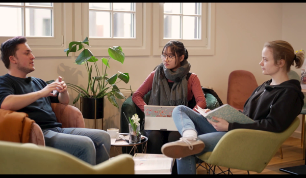 Drei Studierende auf Sesseln, diskutierend
