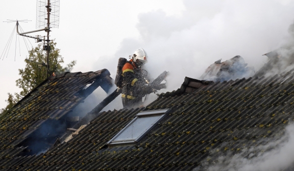 Feuerwehrmann auf Dach eines brennenden Hauses