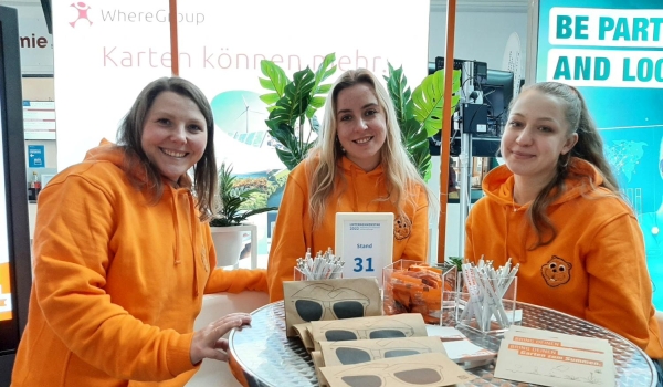Drei Damen in orangen Hoodies an einem Stand des Unternehmenstags in Sankt Augustin