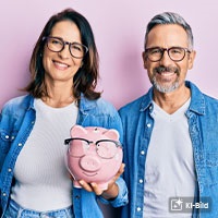 Eine Frau und ein Mann halten l&auml;chelnd ein Sparschwein.